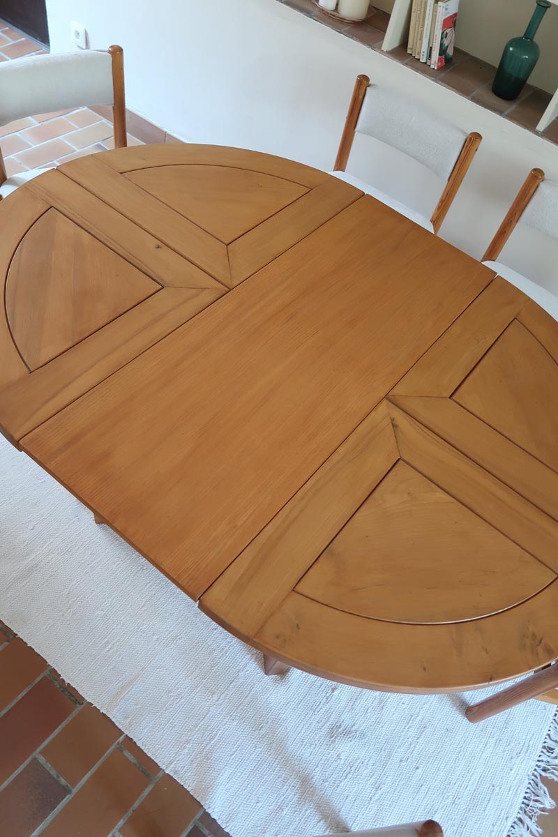 Table ronde extensible en orme massif attribuée à Maison Regain, années 80, plateau à motifs géométriques, rallonge intégrée, patine naturelle.