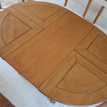 Table ronde extensible en orme massif attribuée à Maison Regain, années 80, plateau à motifs géométriques, rallonge intégrée, patine naturelle.