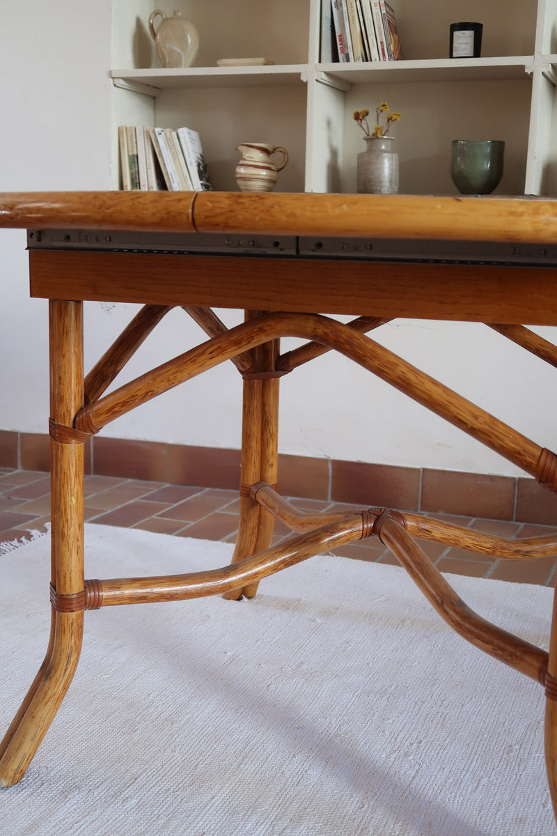 Table à manger ovale extensible bois clair piètement rotin années 70, rallonge centrale, ligatures cuir, jusqu'à 8 couverts