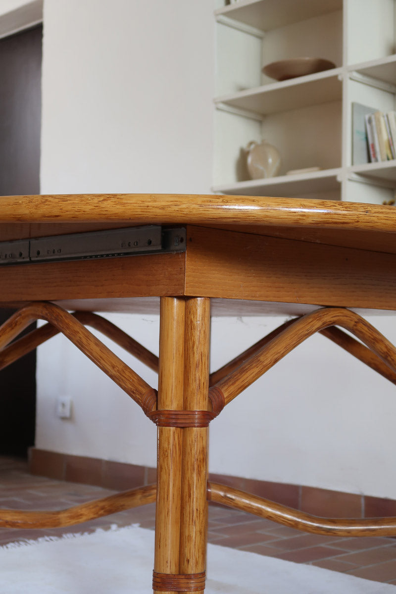 Table à manger ovale extensible bois clair piètement rotin années 70, rallonge centrale, ligatures cuir, jusqu'à 8 couverts