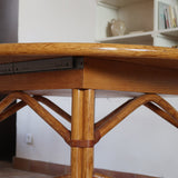 Table à manger ovale extensible bois clair piètement rotin années 70, rallonge centrale, ligatures cuir, jusqu'à 8 couverts