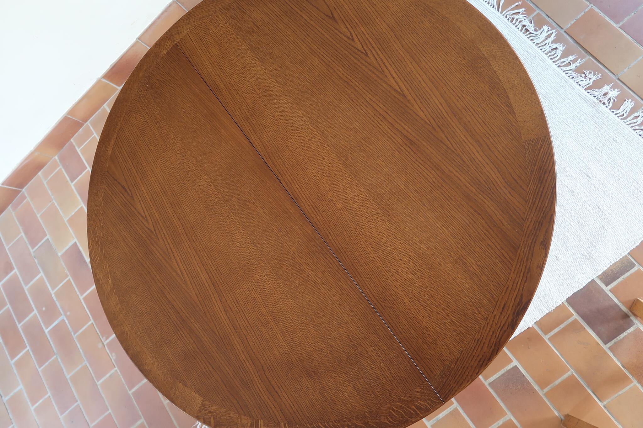 Table ronde vintage à rallonge en chêne massif éditée par Lübke, Allemagne années 60, estampille d'origine sous le plateau, piétement central à quatre jambes plates croisées en X réunies par un moyeu rond, allonge centrale