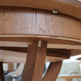 Table ronde vintage à rallonge en chêne massif éditée par Lübke, Allemagne années 60, estampille d'origine sous le plateau, piétement central à quatre jambes plates croisées en X réunies par un moyeu rond, allonge centrale