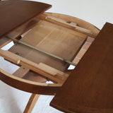 Table ronde vintage à rallonge en chêne massif éditée par Lübke, Allemagne années 60, estampille d'origine sous le plateau, piétement central à quatre jambes plates croisées en X réunies par un moyeu rond, allonge centrale