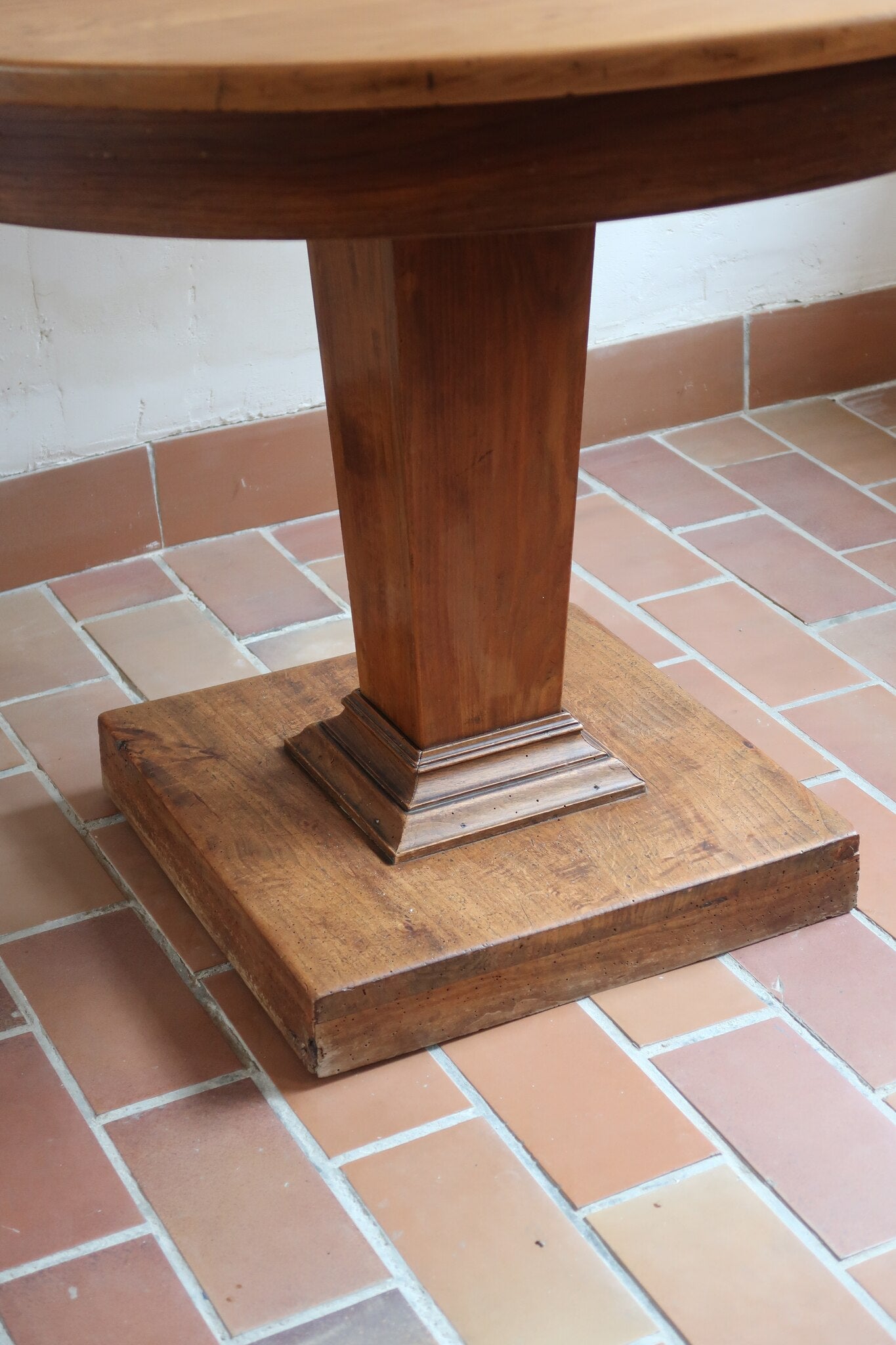Table ronde vintage en frêne art déco, plateau circulaire à chant arrondi, pied central en colonne carrée sur socle mouluré à degrés, bois traité et rénové