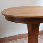 Table ronde vintage en frêne art déco, plateau circulaire à chant arrondi, pied central en colonne carrée sur socle mouluré à degrés, bois traité et rénové