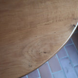 Table ronde vintage en frêne art déco, plateau circulaire à chant arrondi, pied central en colonne carrée sur socle mouluré à degrés, bois traité et rénové
