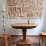Table ronde vintage en frêne art déco, plateau circulaire à chant arrondi, pied central en colonne carrée sur socle mouluré à degrés, bois traité et rénové