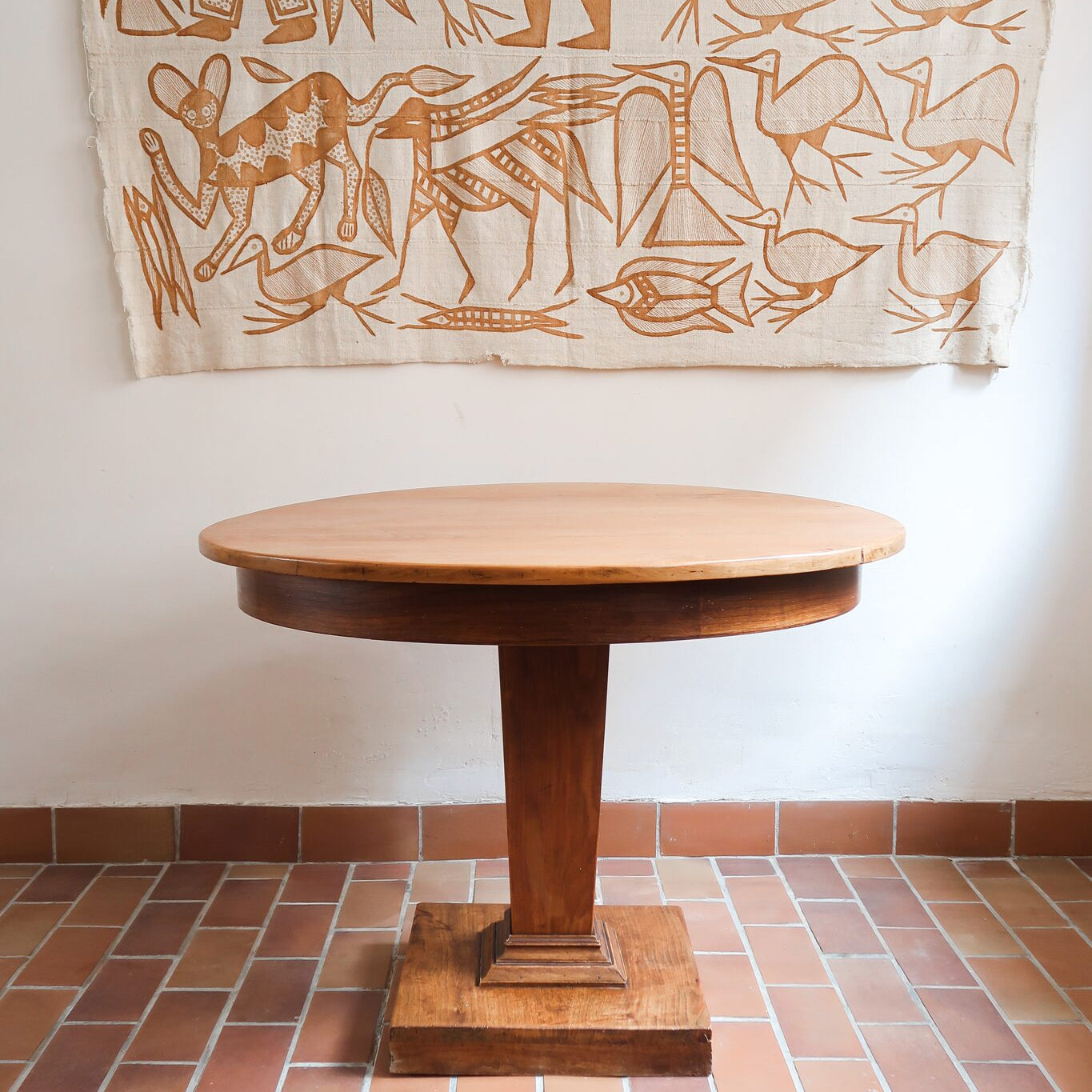 Table ronde vintage en frêne art déco, plateau circulaire à chant arrondi, pied central en colonne carrée sur socle mouluré à degrés, bois traité et rénové