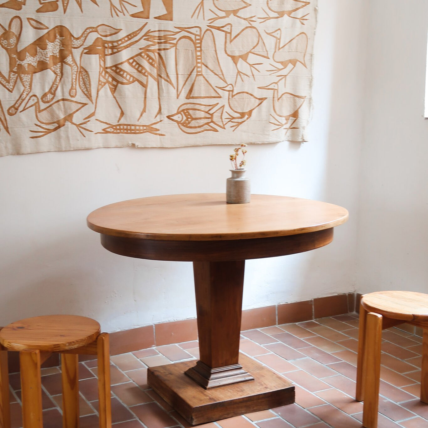 Table ronde vintage en frene art déco, plateau circulaire à chant arrondi, pied central en colonne carrée sur socle mouluré à degrés, bois traité et rénové