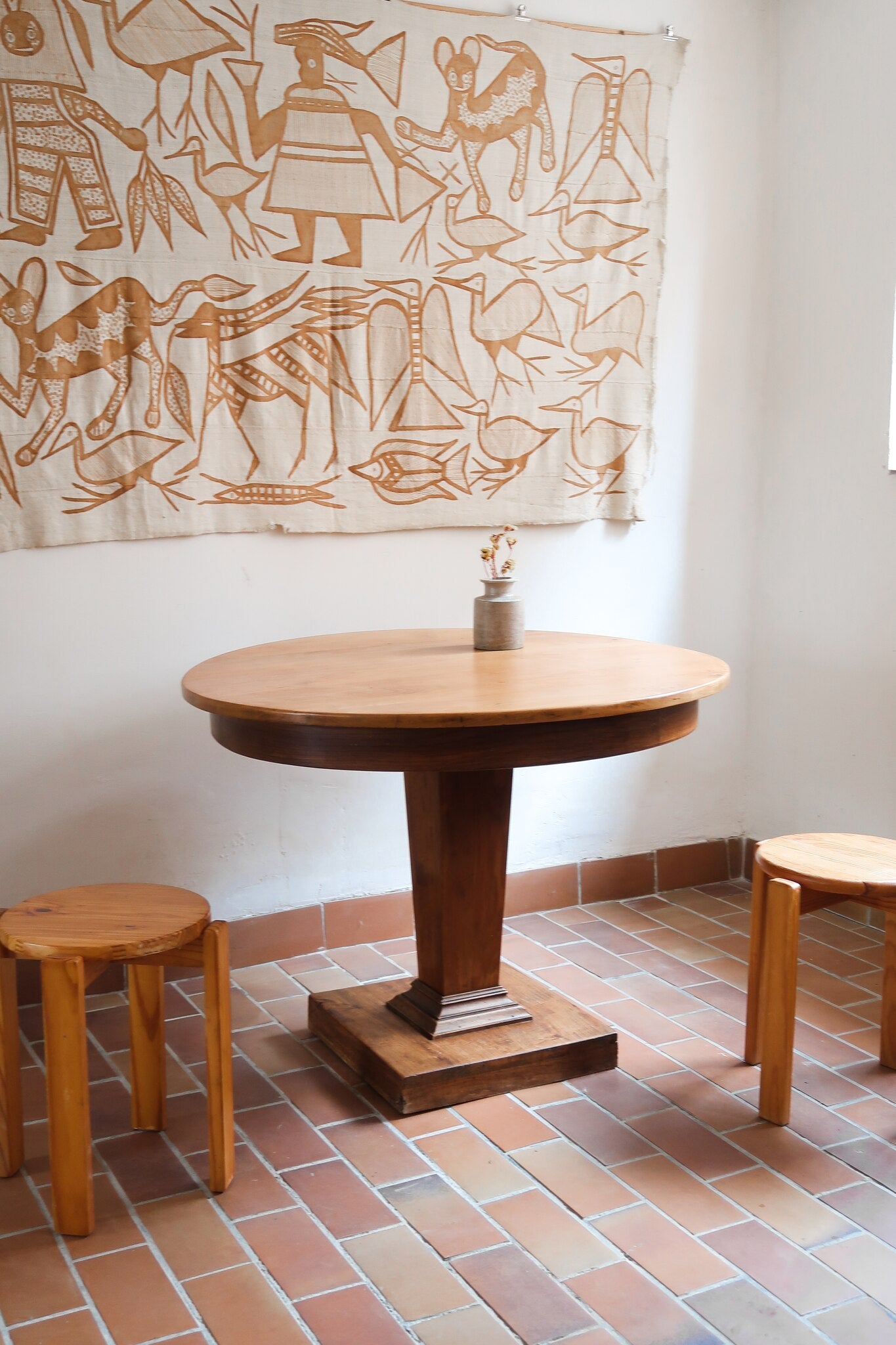 Table ronde vintage en frene art déco, plateau circulaire à chant arrondi, pied central en colonne carrée sur socle mouluré à degrés, bois traité et rénové