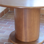 Table ronde vintage en bois blond, années 90, plateau de 118 cm posé sur un gros fût cylindrique plein cerclé d'une base ronde en retrait, esprit Art déco