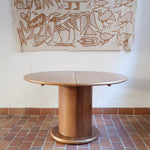 Table ronde vintage en bois blond, années 90, plateau de 118 cm posé sur un gros fût cylindrique plein cerclé d'une base ronde en retrait, esprit Art déco