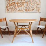 Table ronde vintage en rotin et bois clair, années 70, piètement tressé avec ligatures, plateau en bois patiné.