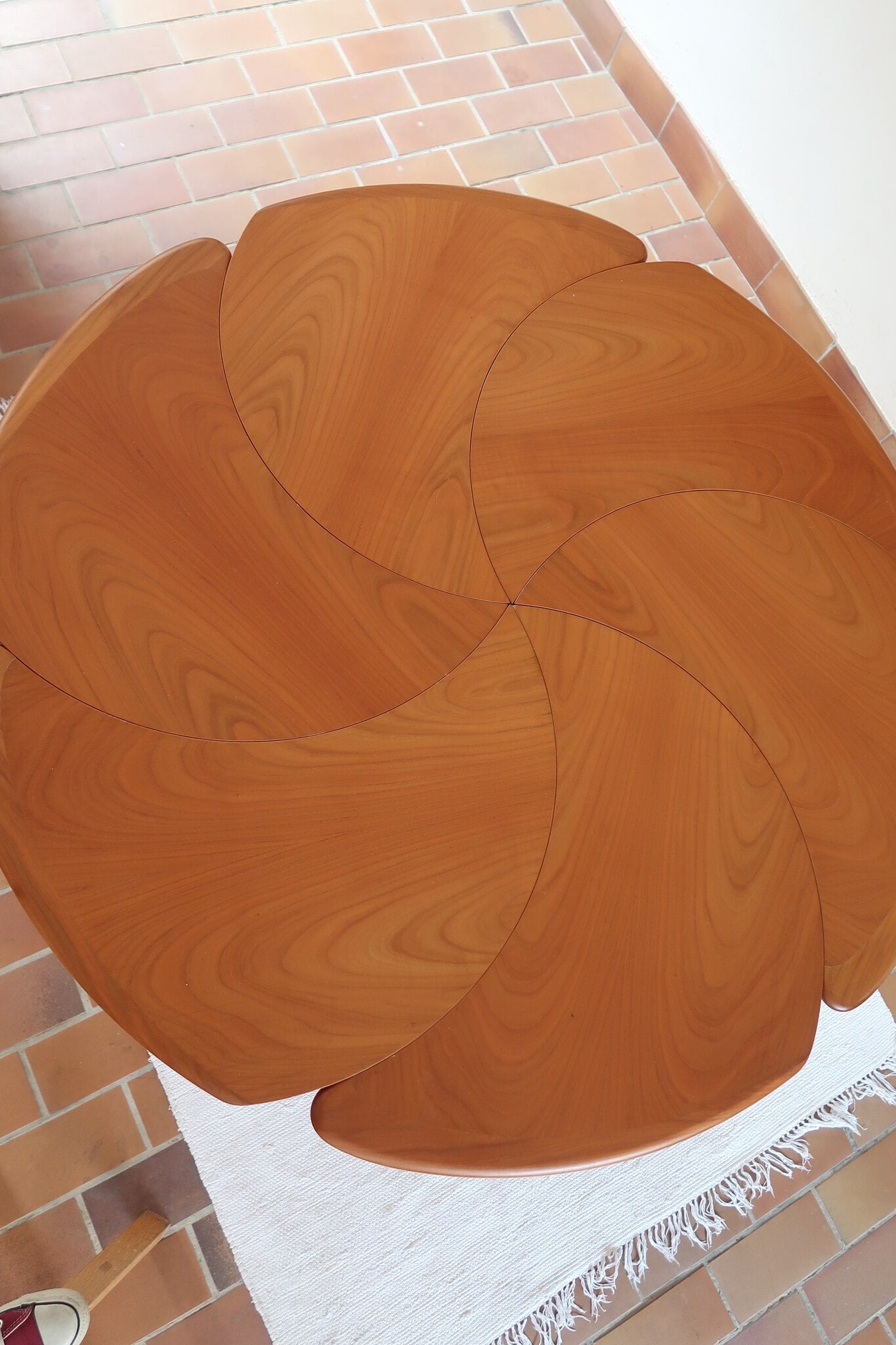Table ronde vintage en orme massif années 80, prototype jamais produit, plateau fixe composé de six segments dessinés en pétales autour du centre, piétement central à quatre jambes larges cintrées