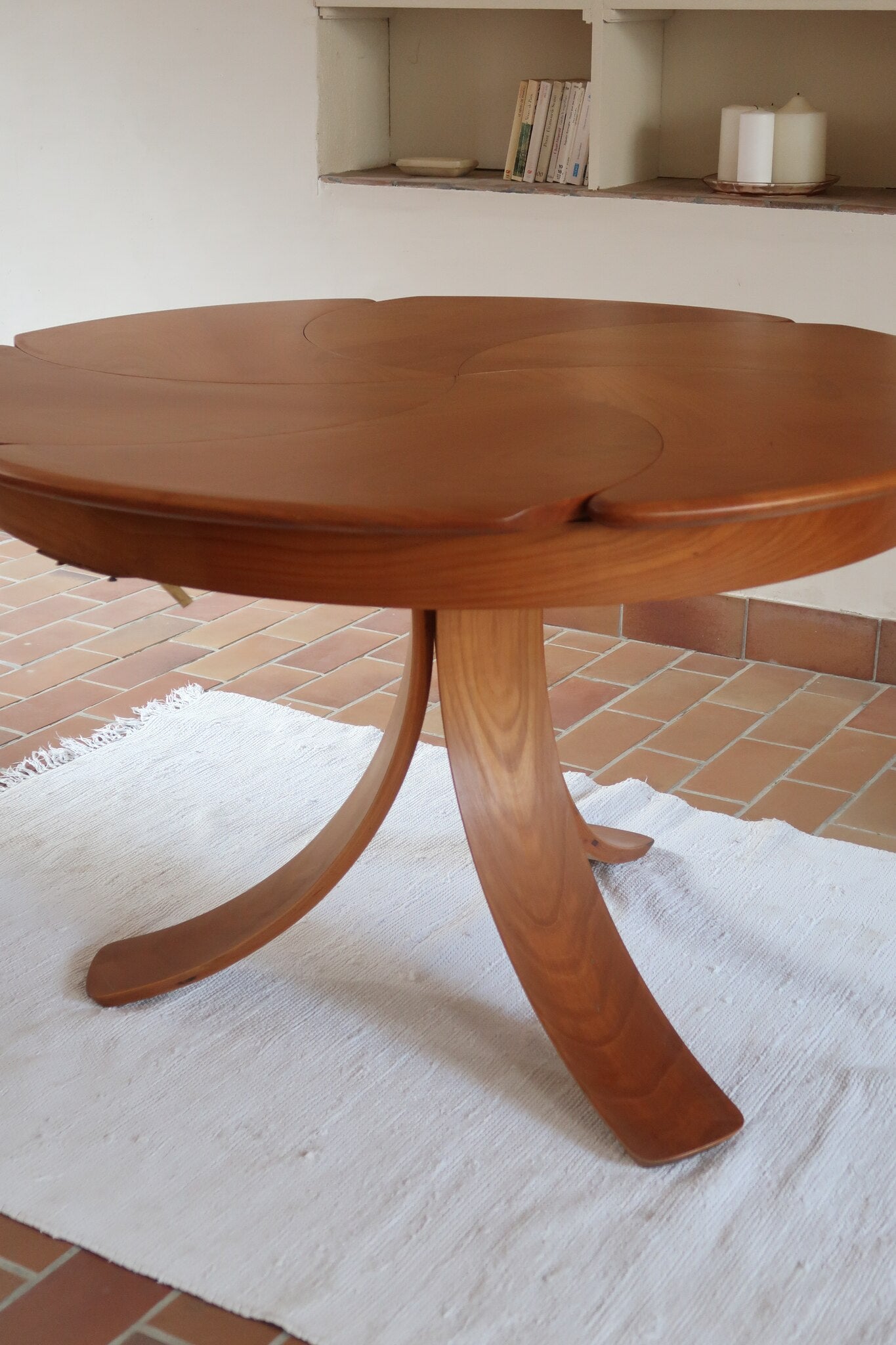 Table ronde vintage en orme massif années 80, prototype jamais produit, plateau fixe composé de six segments dessinés en pétales autour du centre, piétement central à quatre jambes larges cintrées