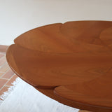 Table ronde vintage en orme massif années 80, prototype jamais produit, plateau fixe composé de six segments dessinés en pétales autour du centre, piétement central à quatre jambes larges cintrées