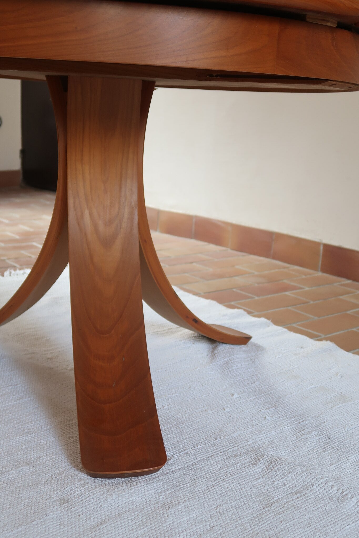 Table ronde vintage en orme massif années 80, prototype jamais produit, plateau fixe composé de six segments dessinés en pétales autour du centre, piétement central à quatre jambes larges cintrées