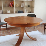 Table ronde vintage en orme massif années 80, prototype jamais produit, plateau fixe composé de six segments dessinés en pétales autour du centre, piétement central à quatre jambes larges cintrées