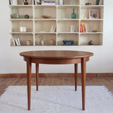 Table à manger ronde extensible vintage en teck miel, pieds fuseau, deux rallonges jusqu'à douze couverts, style scandinave fabrication française années 60