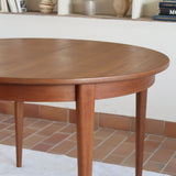Table à manger ronde extensible vintage en teck miel, pieds fuseau, deux rallonges jusqu'à douze couverts, style scandinave fabrication française années 60