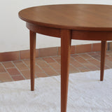 Table à manger ronde extensible vintage en teck miel, pieds fuseau, deux rallonges jusqu'à douze couverts, style scandinave fabrication française années 60