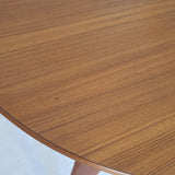 Table à manger ronde extensible vintage en teck miel, pieds fuseau, deux rallonges jusqu'à douze couverts, style scandinave fabrication française années 60