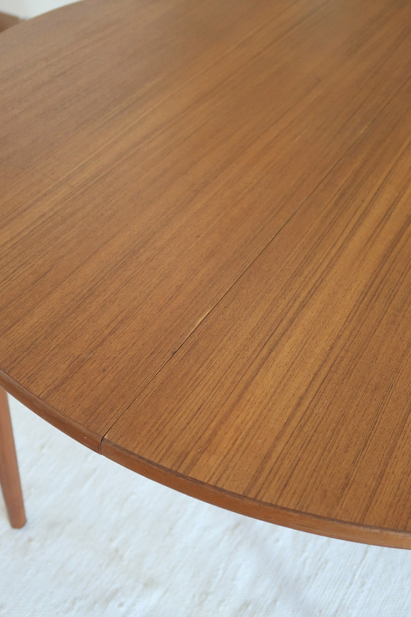 Table à manger ronde extensible vintage en teck miel, pieds fuseau, deux rallonges jusqu'à douze couverts, style scandinave fabrication française années 60