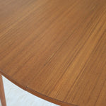 Table à manger ronde extensible vintage en teck miel, pieds fuseau, deux rallonges jusqu'à douze couverts, style scandinave fabrication française années 60