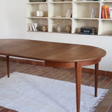 Table à manger ronde extensible vintage en teck miel, pieds fuseau, deux rallonges jusqu'à douze couverts, style scandinave fabrication française années 60