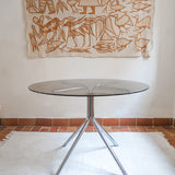 Table ronde années 70 avec plateau en verre fumé et piètement chromé sculptural à quatre branches.
