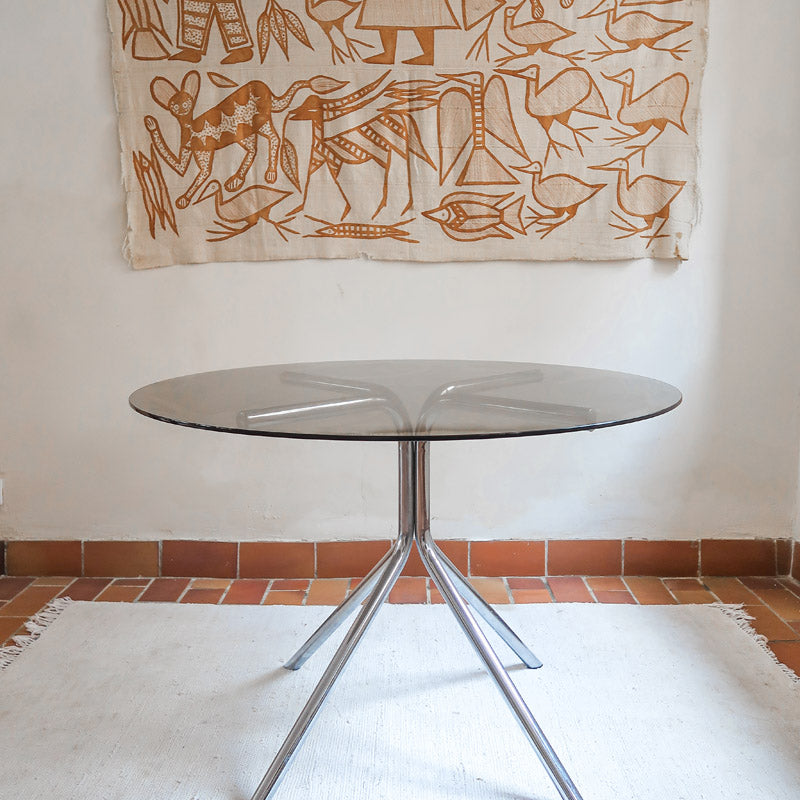 Table ronde années 70 avec plateau en verre fumé et piètement chromé sculptural à quatre branches.