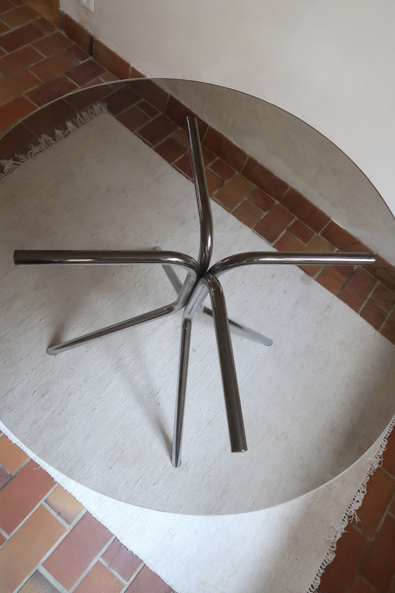 Table ronde années 70 avec plateau en verre fumé et piètement chromé sculptural à quatre branches.