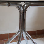Table ronde années 70 avec plateau en verre fumé et piètement chromé sculptural à quatre branches.