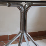 Table ronde années 70 avec plateau en verre fumé et piètement chromé sculptural à quatre branches.