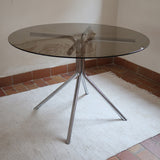 Table ronde années 70 avec plateau en verre fumé et piètement chromé sculptural à quatre branches.