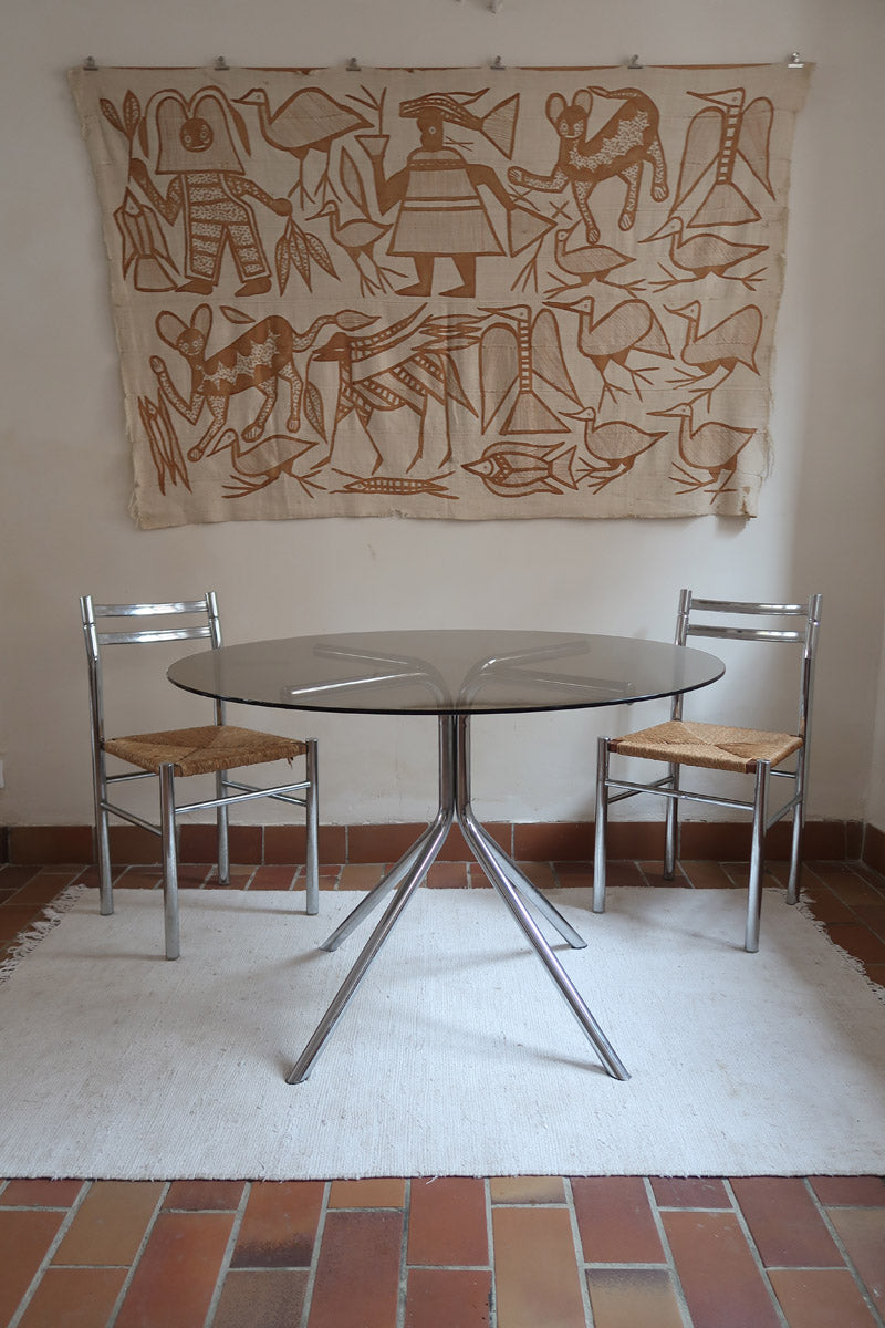 Table ronde années 70 avec plateau en verre fumé et piètement chromé sculptural à quatre branches.