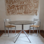 Table ronde années 70 avec plateau en verre fumé et piètement chromé sculptural à quatre branches.