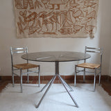 Table ronde années 70 avec plateau en verre fumé et piètement chromé sculptural à quatre branches.