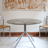 Table ronde années 70 avec plateau en verre fumé et piètement chromé sculptural à quatre branches.