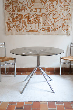 Table ronde années 70 avec plateau en verre fumé et piètement chromé sculptural à quatre branches.