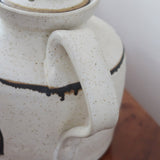 Théière grès émaillé artisanal années 70, décor peint main trèfle quatre feuilles, blanc cassé moucheté brun doré, liseré noir col, tournée main